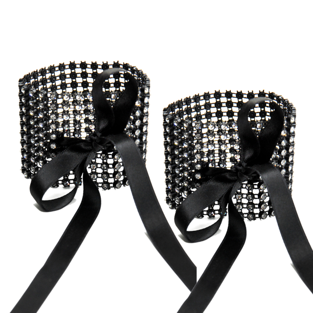 Noble cuffs made of fine black lattice, symmetrically set with colourless rhinestones. To be closed with a narrow satin ribbon.